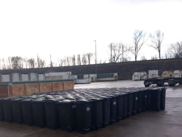 Rij gereinigde rolcontainers achter een zorginstelling